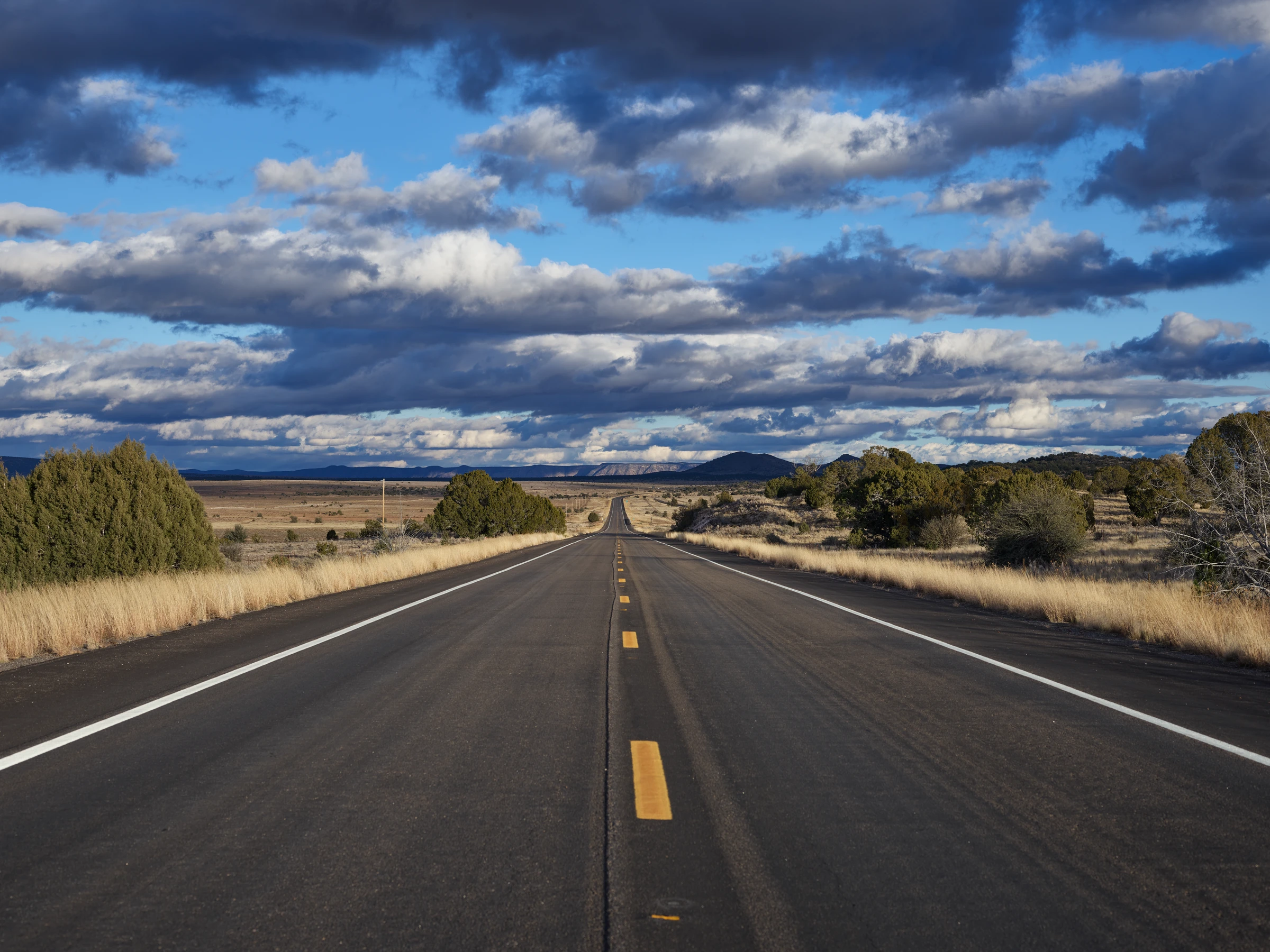 Historic Route 66 stretching across the Arizona high desert under a wide, cloud-filled sky.